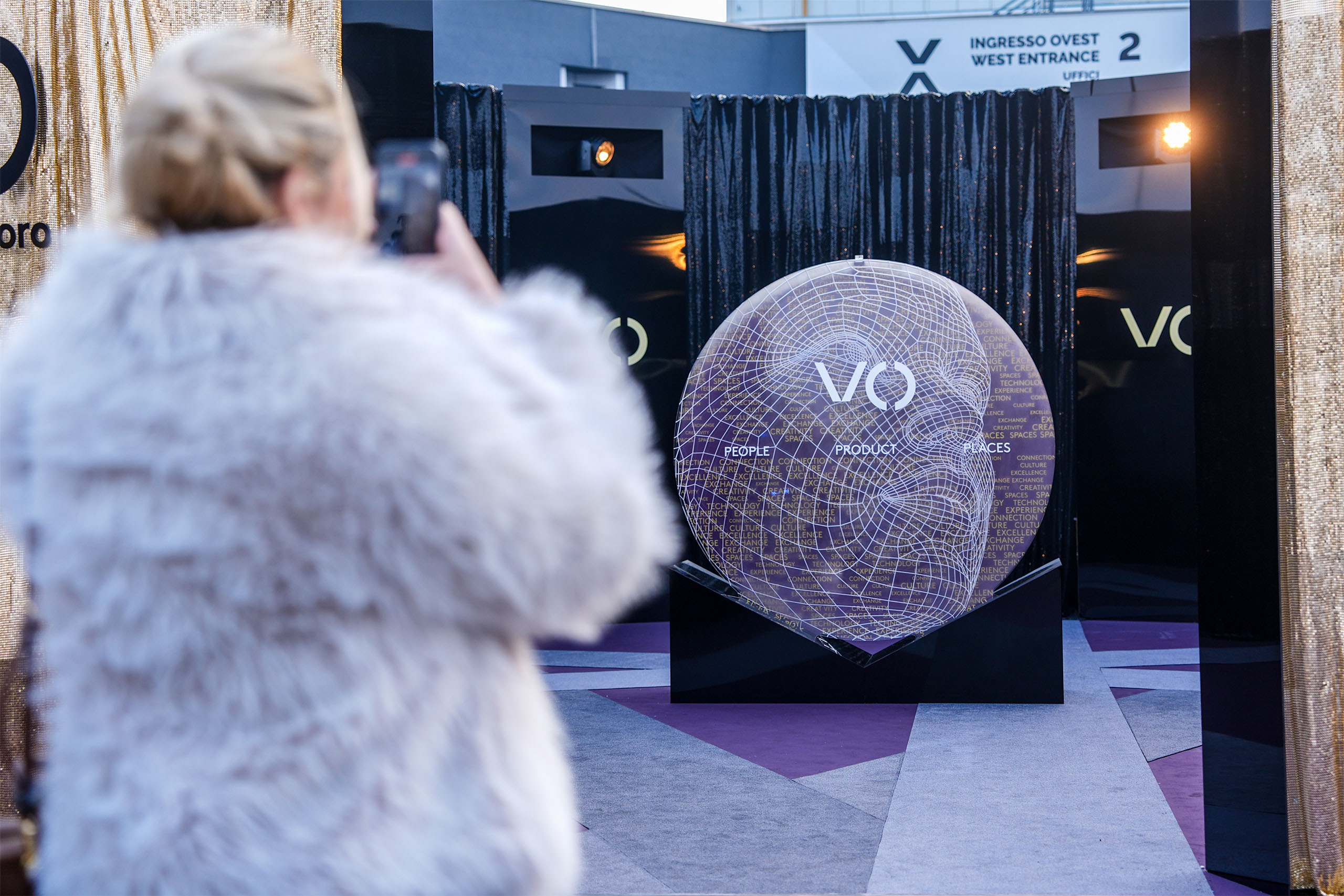 Visitatrice fotografa sfera filare con logo VO Vicenzaoro all'ingresso ovest della fiera
