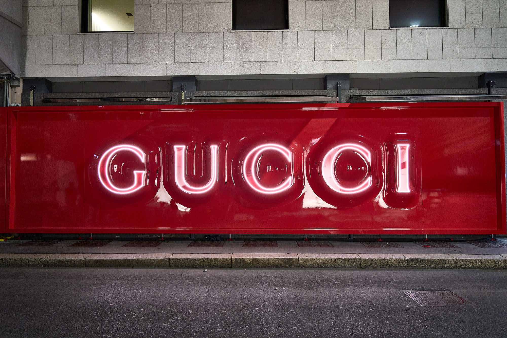 Insegna Gucci neon rosa su fondo rosso total red per restyling store Milano
