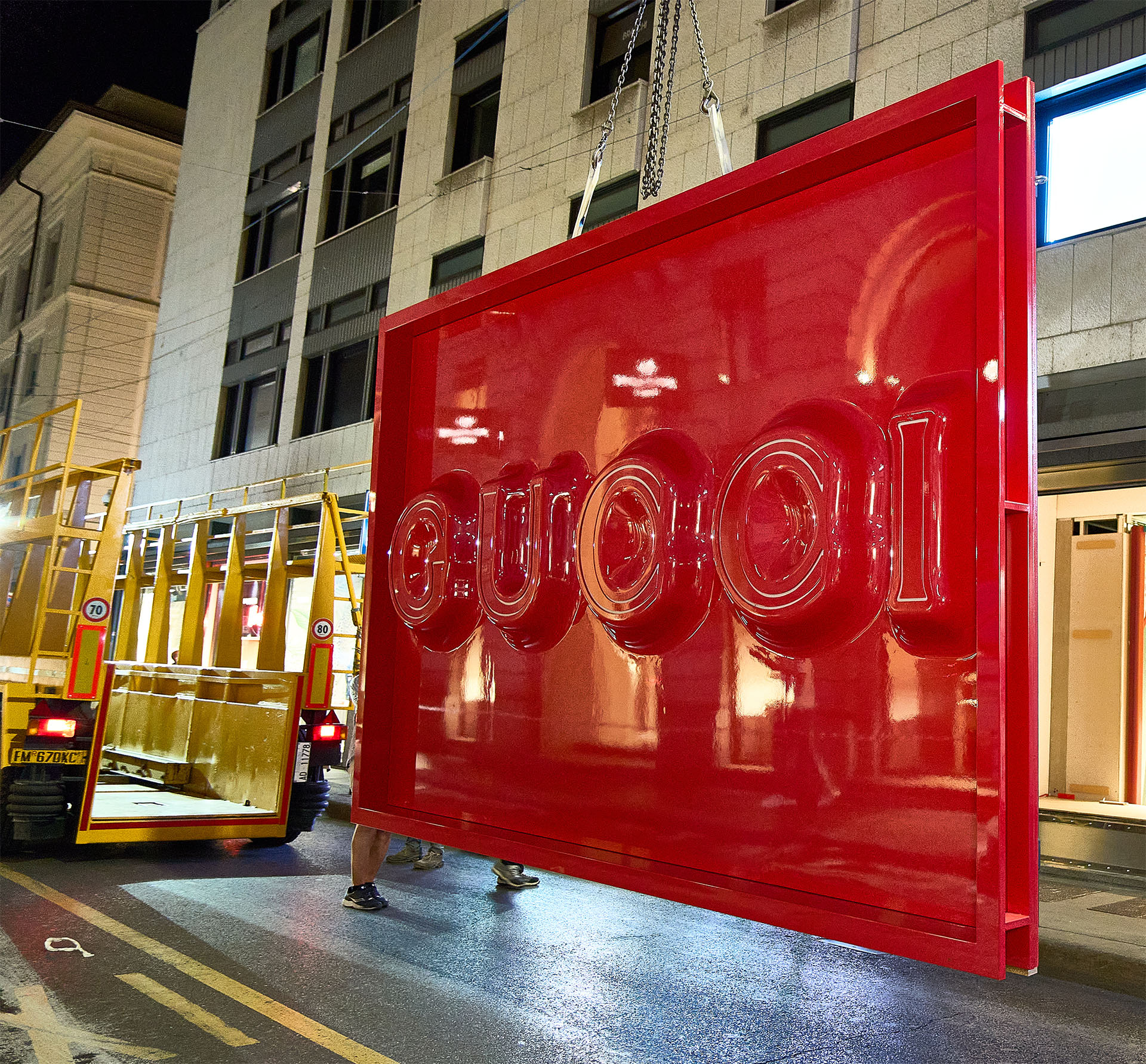 Pannello rosso lucido con scritta Gucci 3D in trasporto notturno per restyling store Milano