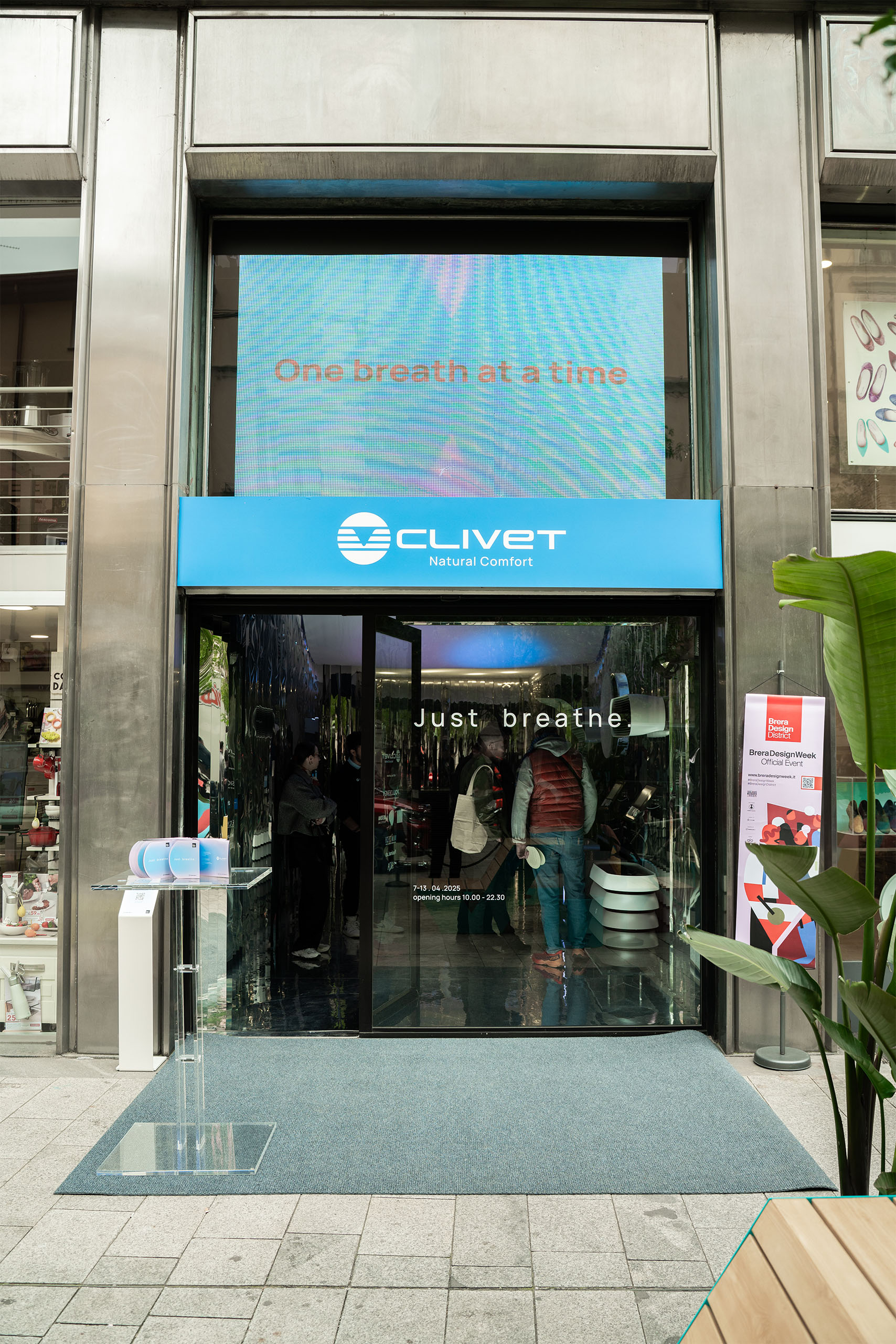 Ingresso Clivet al Fuorisalone 2025 Just Breathe: insegna blu e schermo One breath at a time
