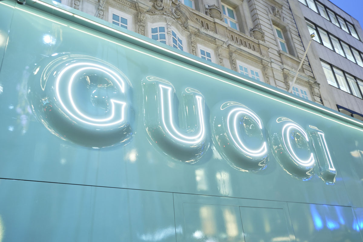 Vetrina Gucci a Londra con scritta neon a effetto bolle d'acqua su fondo verde menta