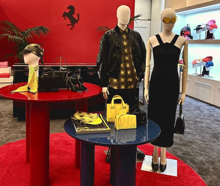 Interno Ferrari Boutique Las Vegas con manichini, borse gialle, parete rossa e cavallino rampante