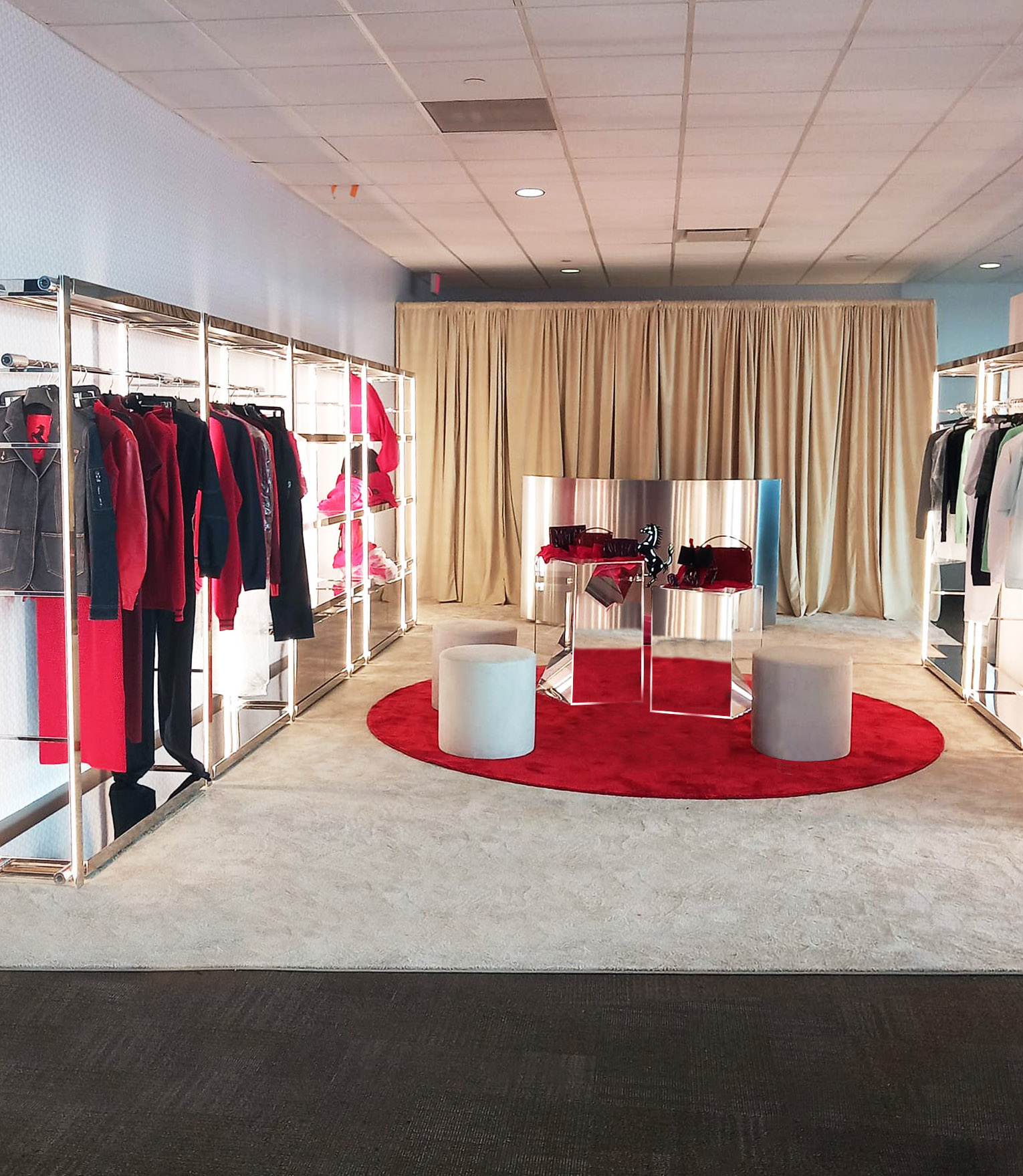 Pop-up store Ferrari Challenge COTA 2024: rack con capi rossi e neri e podio specchiato su tappeto rosso
