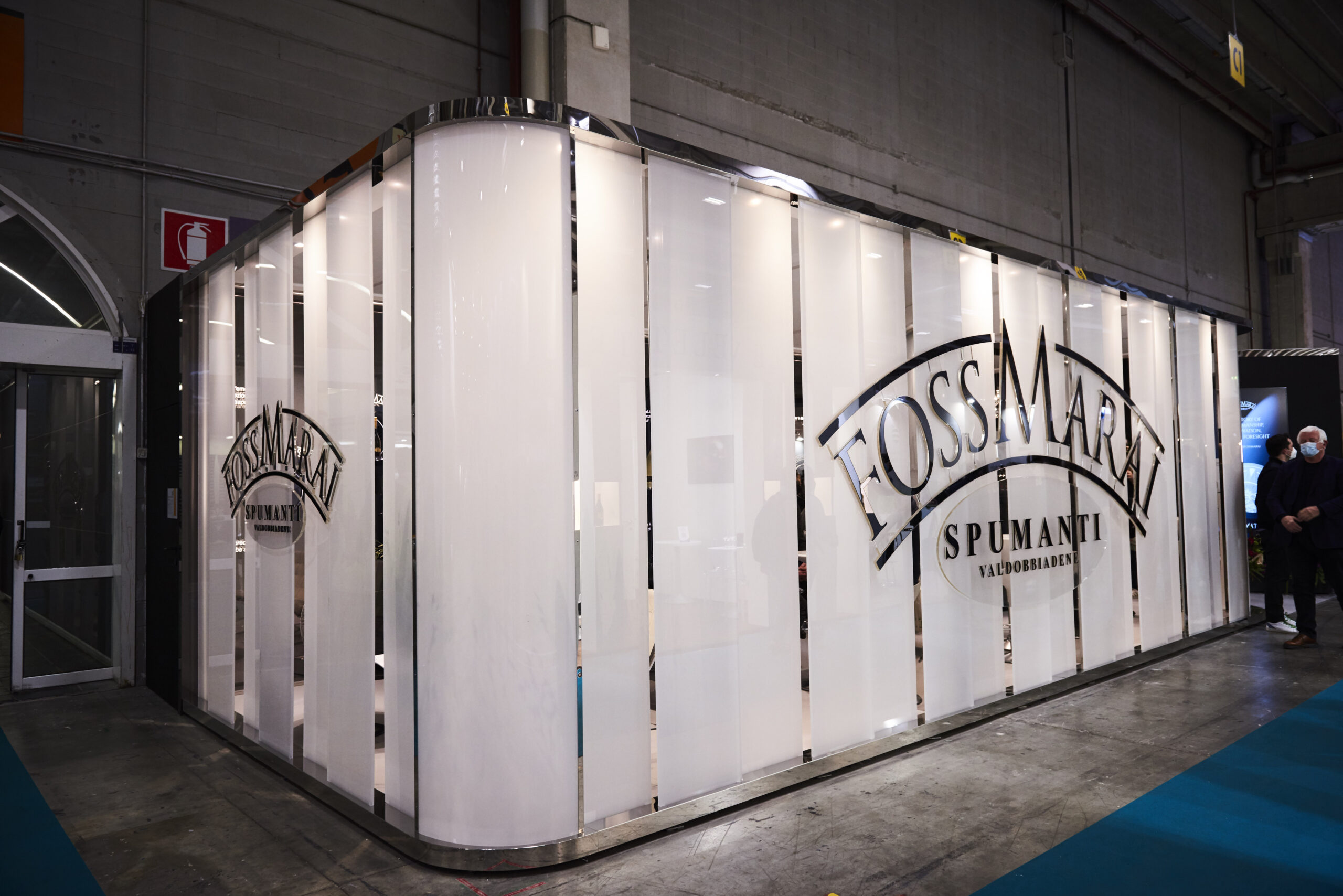 Stand Foss Marai Spumanti Valdobbiadene a Vinitaly con pareti retroilluminate e logo dorato